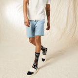 Person wearing light blue shorts and patterned socks on a neutral background thumbnail