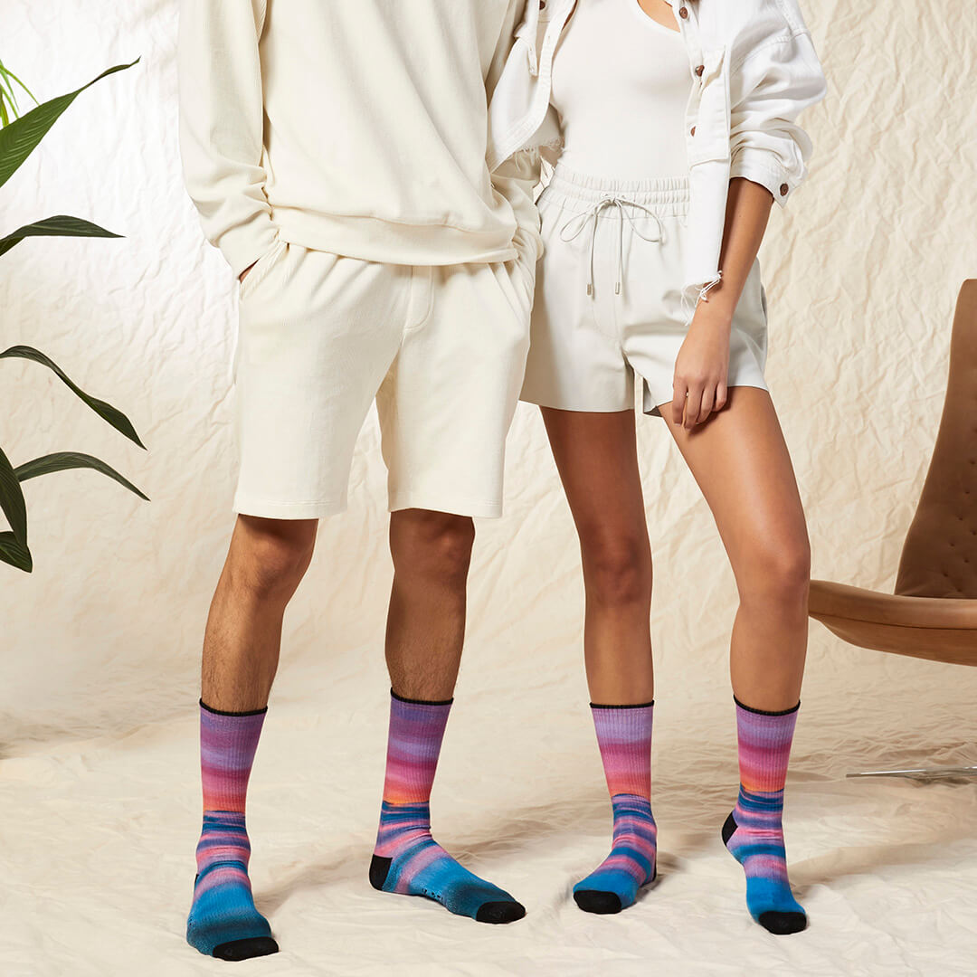 Two people wearing matching white outfits with colorful socks in a casual setting.