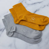 Two pairs of metallic socks, one gold and one silver, on a marble surface. thumbnail