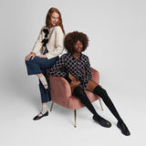 Two women sitting in fashionable outfits with k.bell socks on a pink chair against a plain background thumbnail