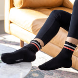 Person wearing black socks with striped cuffs in a living room setting thumbnail