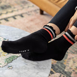 Person wearing black socks with pink and white stripes, sitting on a marble surface. thumbnail