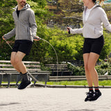 Two people jumping rope in a park with trees and benches in the background. thumbnail