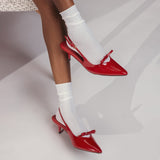 Red high-heeled shoes worn with white socks on a neutral background thumbnail
