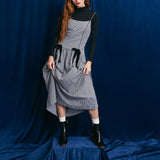 Person wearing a gray checkered dress with black accents against a blue backdrop thumbnail