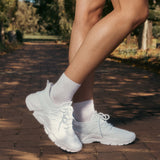 White sneakers and socks worn outdoors on a brick path