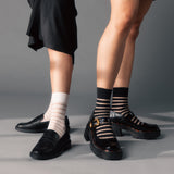 Two pairs of legs wearing black shoes and striped socks on a gray background