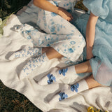 Two people sitting on a blanket wearing matching floral outfits and socks.