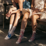 Two people sitting on a bench wearing floral socks.